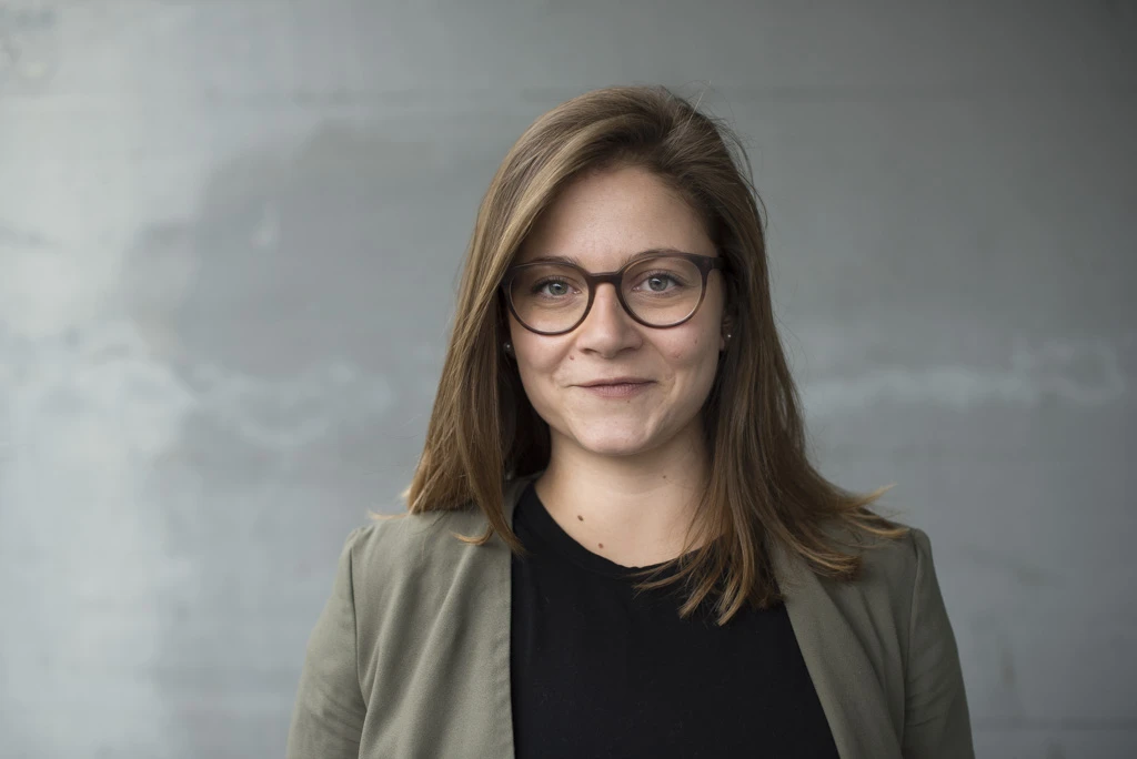 An informal headshot of a young professional woman, grey background. taken in Winterthur, Switzerland